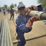 Workers carry pipe as they drill a well on April 7, 2017, in Rumading, a village in South Sudan's Lol State where more than 5,000 people, displaced by drought and conflict, remain in limbo. In early 2017, they set out walking for Sudan, seeking better conditions, but were stopped from crossing the border. They remain camped out under the trees at Rumading, eating wild leaves as the rainy season approaches. In early April, Norwegian Church Aid, a member of the ACT Alliance, began drilling the well in the informal settlement and distributed sorghum, beans and cooking oil to the most vulnerable families. The ACT Alliance is carrying out the emergency assistance in coordination with government officials and the local Catholic parish. South Sudan. Photo: Paul Jeffrey/ACT